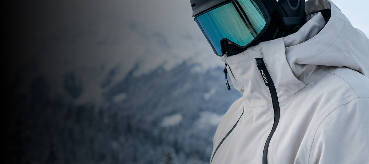 Person with ski anorak and ski goggles standing in front of mountains